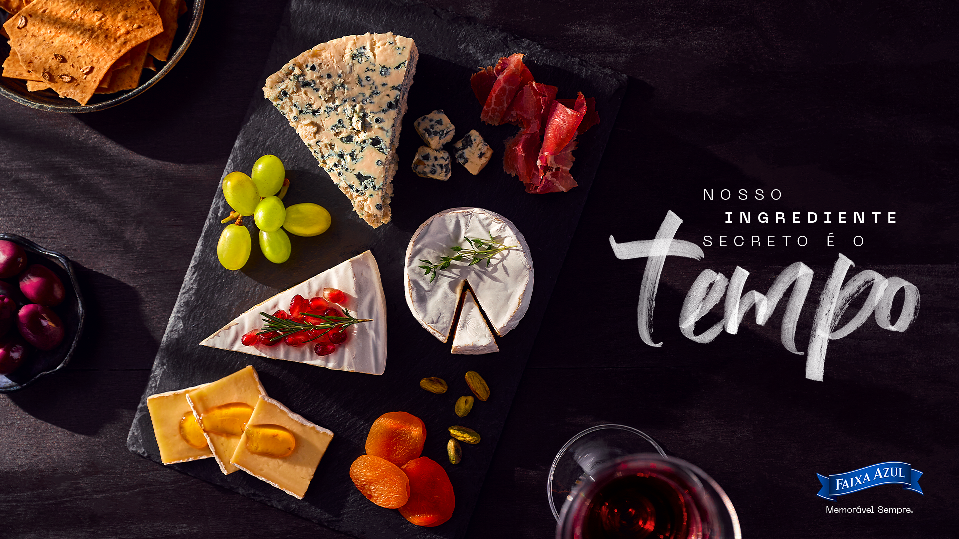 Faixa Azul cheese board with a selection of cheeses, fruit and accompaniments photographed from above on a dark background.