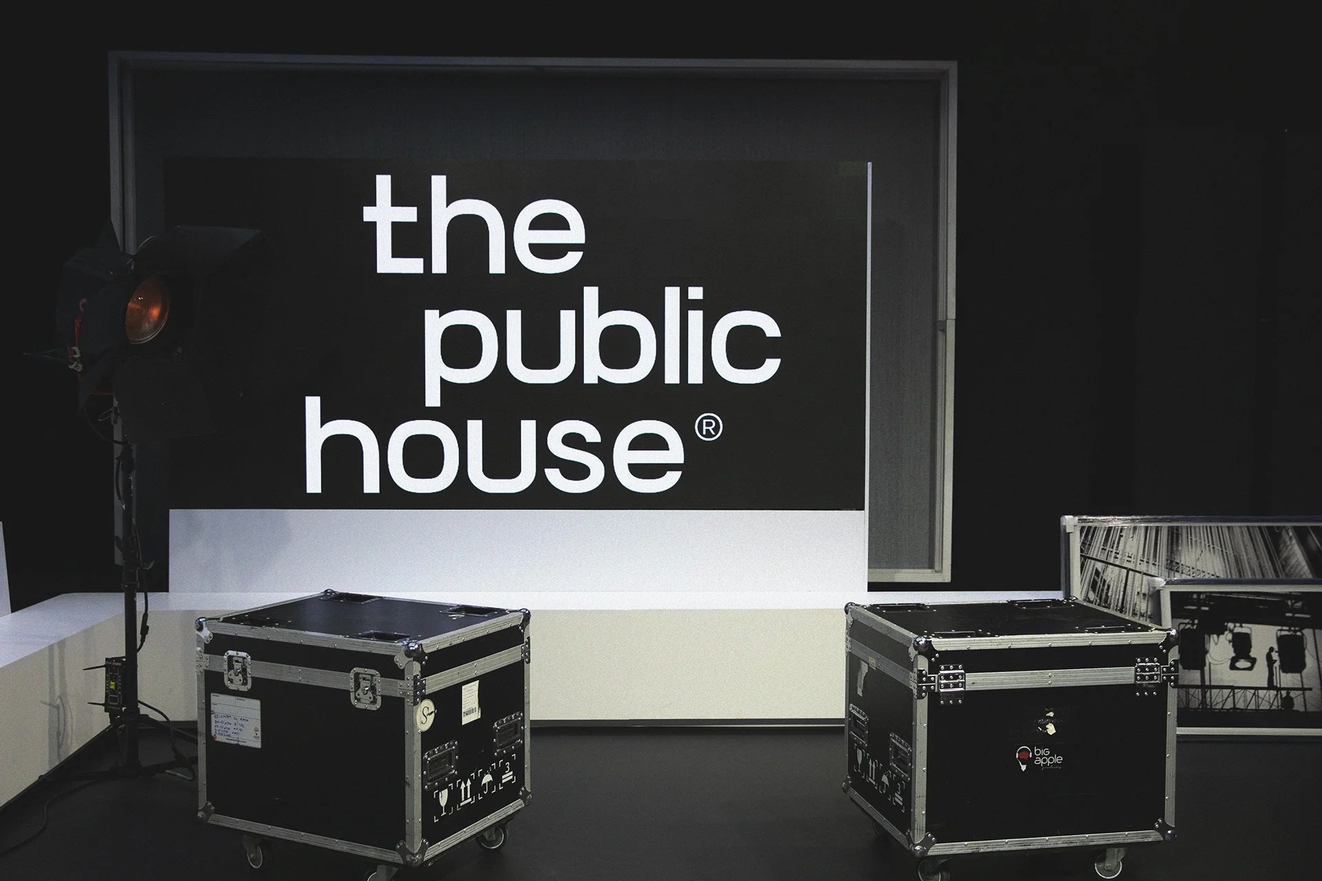 The Public House studio stage with the wordmark on an illuminated backdrop and equipment cases in the foreground.