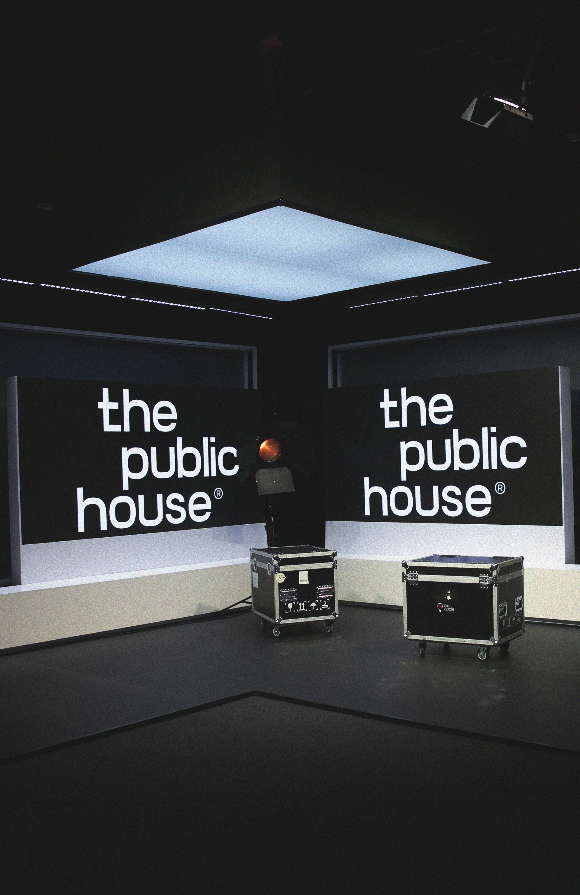 The Public House production studio with illuminated ceiling panels, equipment cases and the wordmark displayed on black walls.