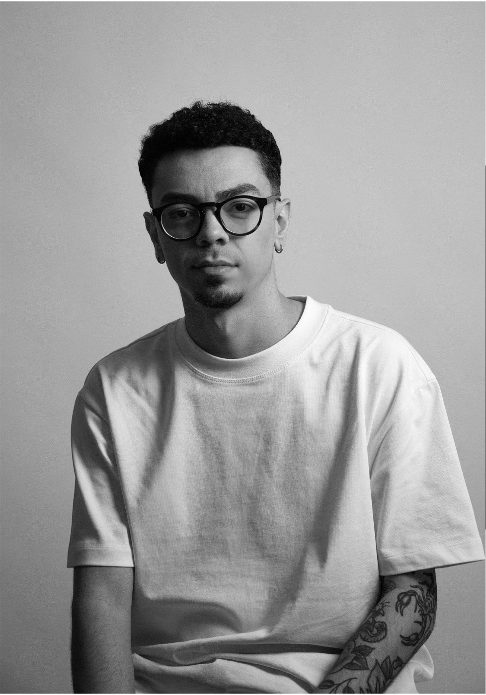 Black and white portrait of Bruno Barone wearing glasses and a white T-shirt.