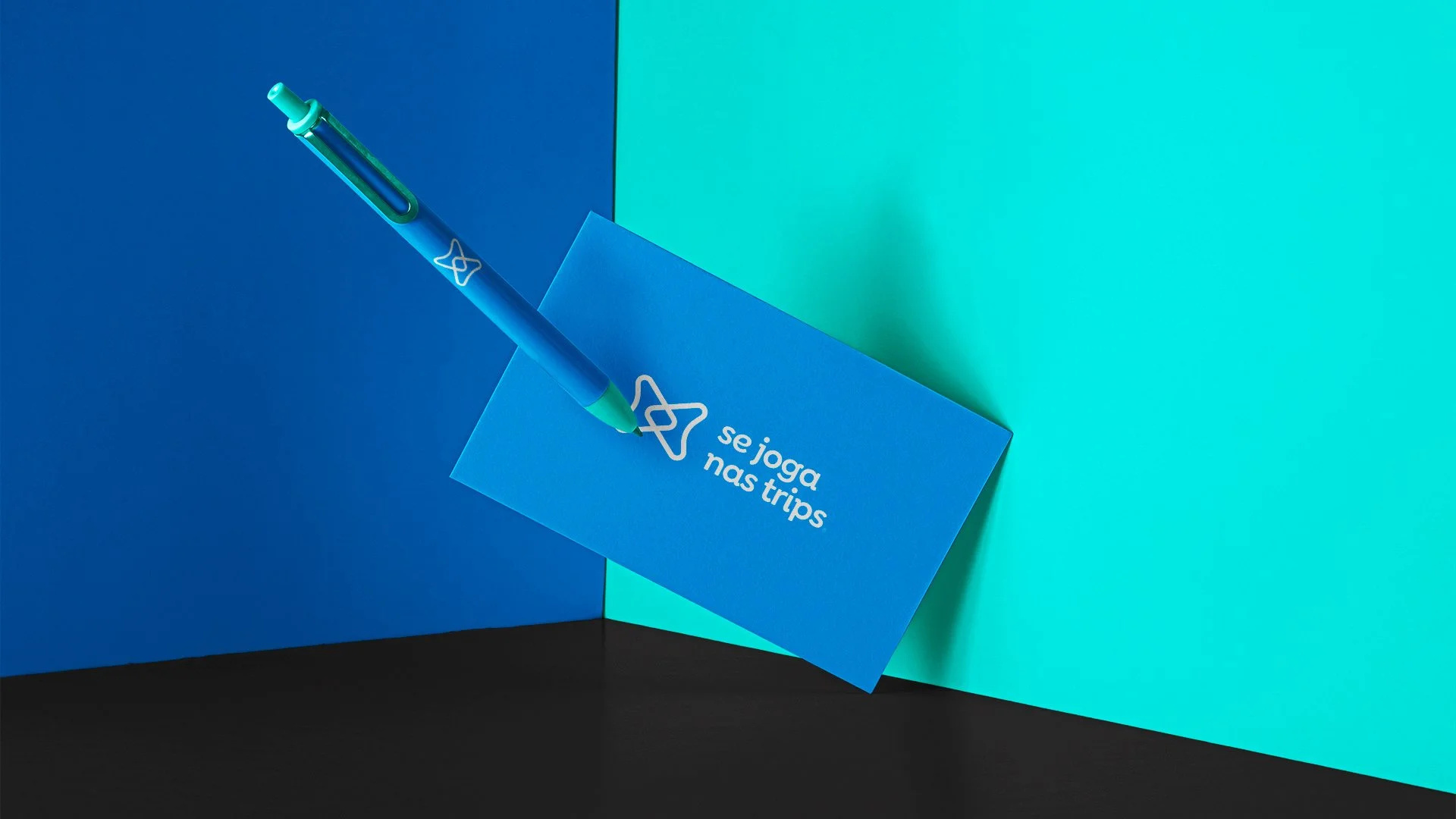 Se Joga Nas Trips blue business card and branded pen against blue, turquoise and black panels.